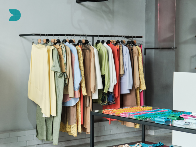 colored clothes hanging from a rack displaying in a fashion store